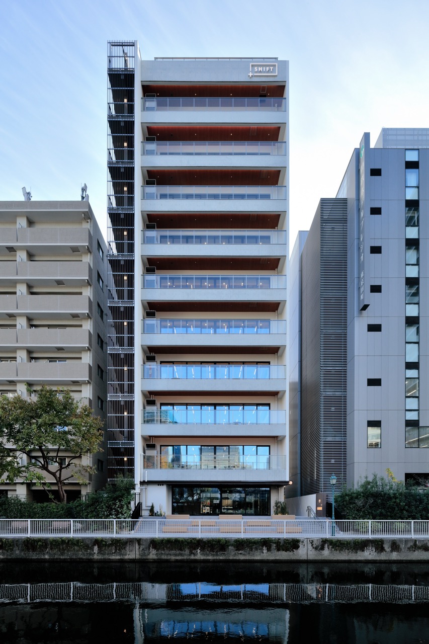 各階にバルコニーがあり、川沿いに建つスマートな外観のオフィスビル