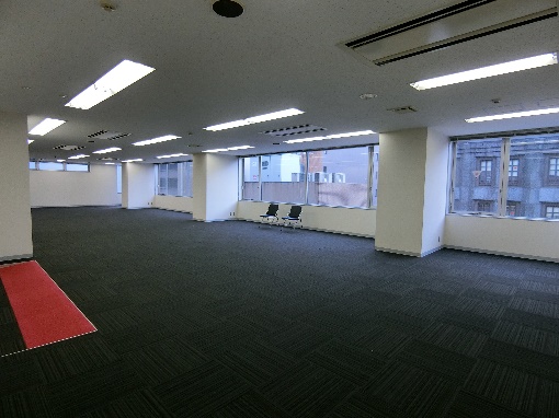 赤いカーペットが敷かれた、改装前の広々としたオフィス空間。