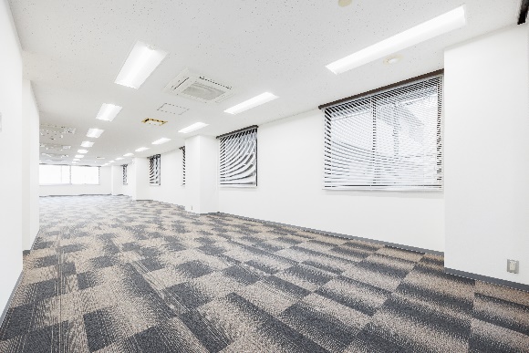 グレーと黒の市松模様のカーペットが敷かれた、空のオフィス空間。