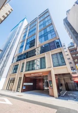 可看到上方標示著建築物名稱的入口，玻璃帷幕的現代高層建築。