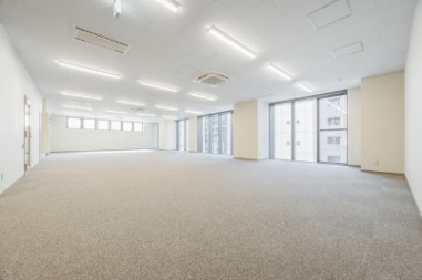 A spacious, empty office space with gray carpeting.