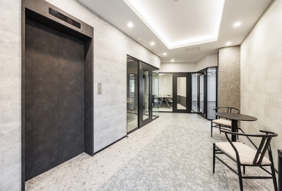 A modern elevator lobby with a small waiting area featuring a table and chairs.