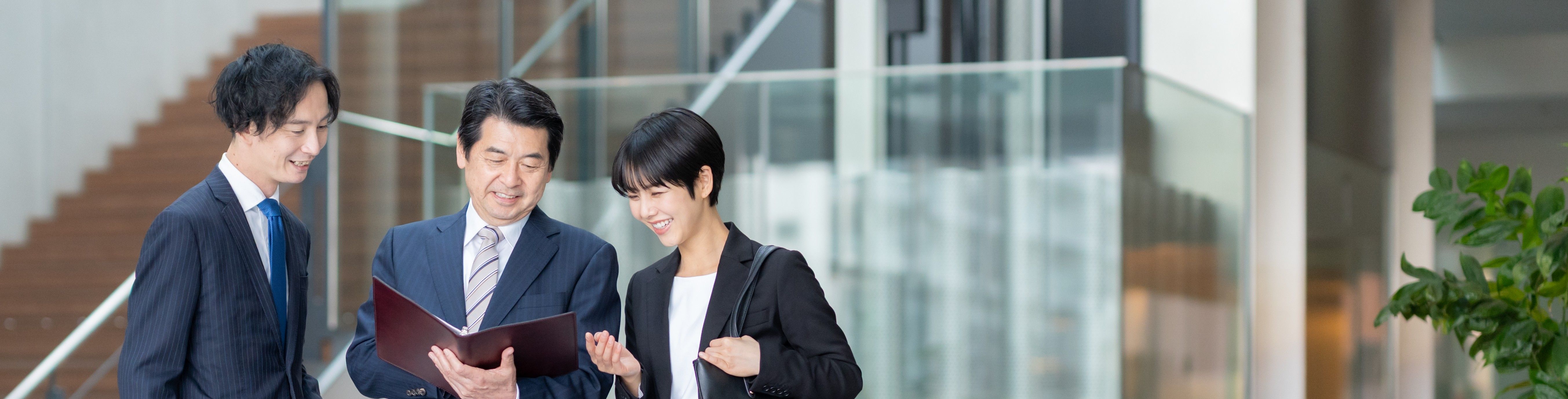 Three business people discussing documents in an office.